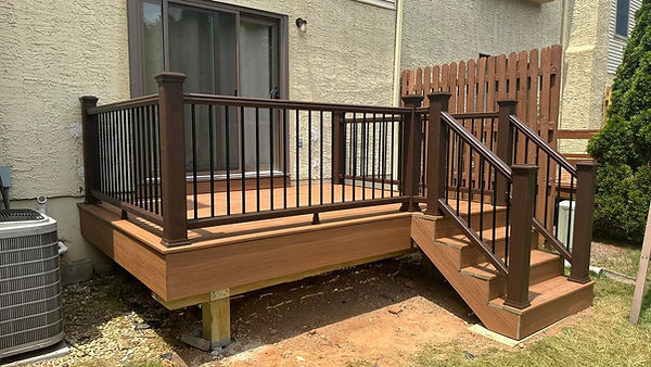 A newly built, low-profile composite deck with brown railings and a short staircase in Boyertown, PA.
