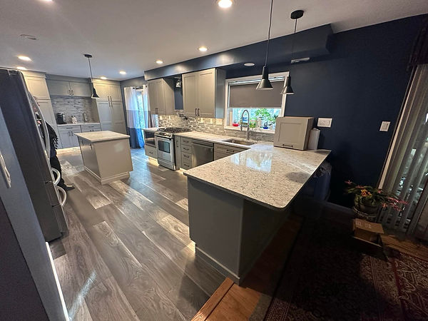 A spacious kitchen in Gilbertsville, PA, with light gray cabinets, a navy blue accent wall, a peninsula, and a separate islan