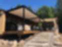 Pergola bioclimatique adossée à une maison moderne avec terrasse aménagée dans les Laurentides