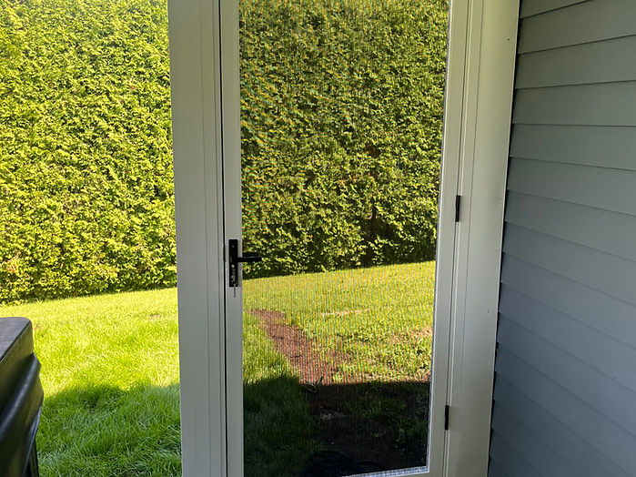 Porte battante vitrée blanche donnant accès à une cour arrière
