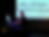 Man plays piano in a dark room as a projected sheet music score fills the screen behind him.