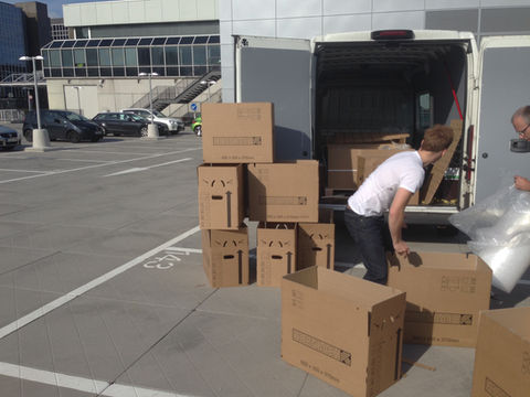 Transportretter Kurierdienst Mitarbeiter männloch packt Kisten in einen weißen Transporter