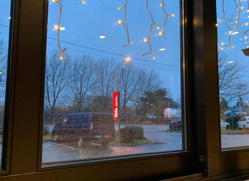 Abendlicher Blick durchs Fenster auf Parkplatz
