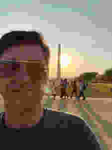Selfie of Mike, wearing aviators with the Washington Monument and the sun setting behind him