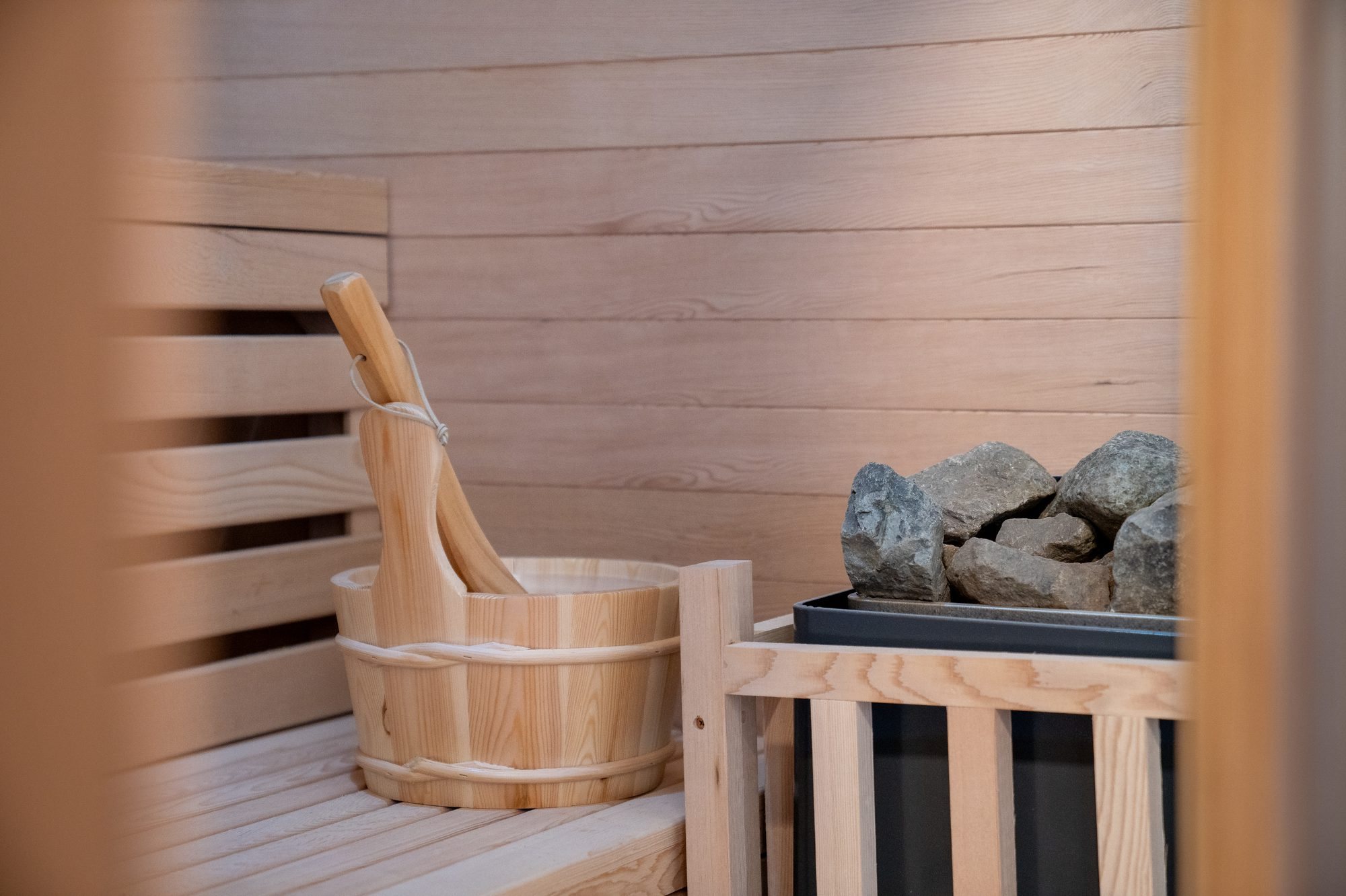 Timber sauna interior with bucket and heater stones