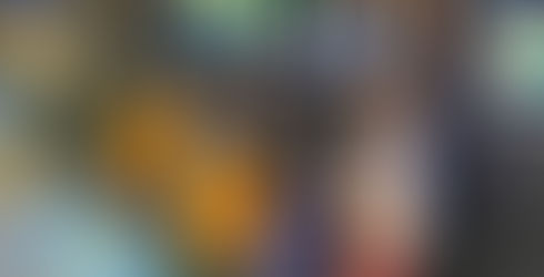 A group of five children using chalk to write on a piece of black butcher paper taped to the wall