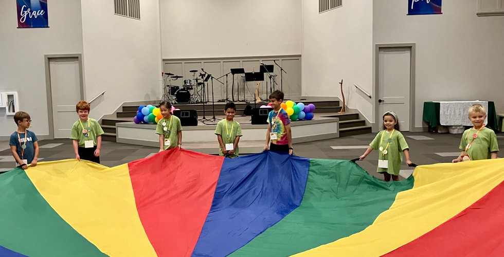 A colorful parachute is being held up by children around the edge