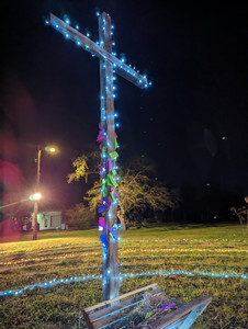 A cross covered in multicolored lights and pieces of paper