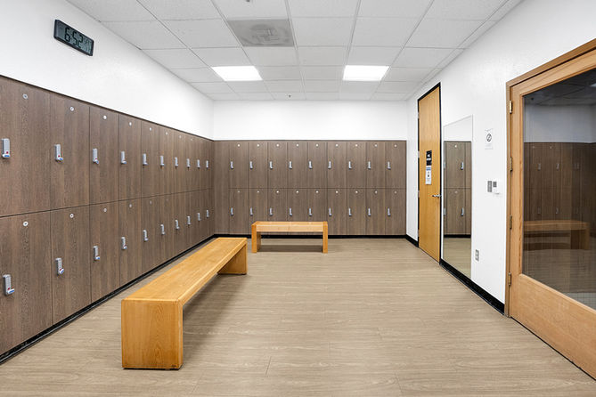 Wooden lockers and benches in a spacious changing room, neutral lighting.