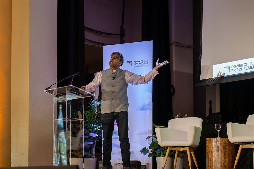 Dr. Raj Patel gesturing while speaking on stage at the Power of Procurement summit