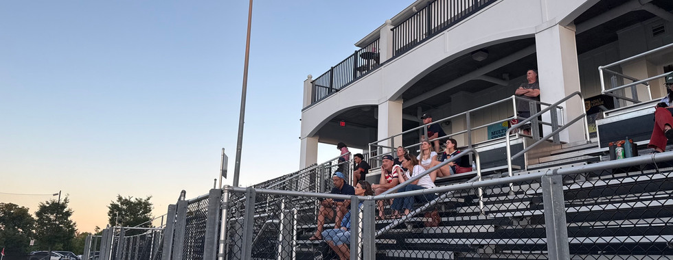 Fans in the stands at RavenTek Park, with the rooftop bar above them 