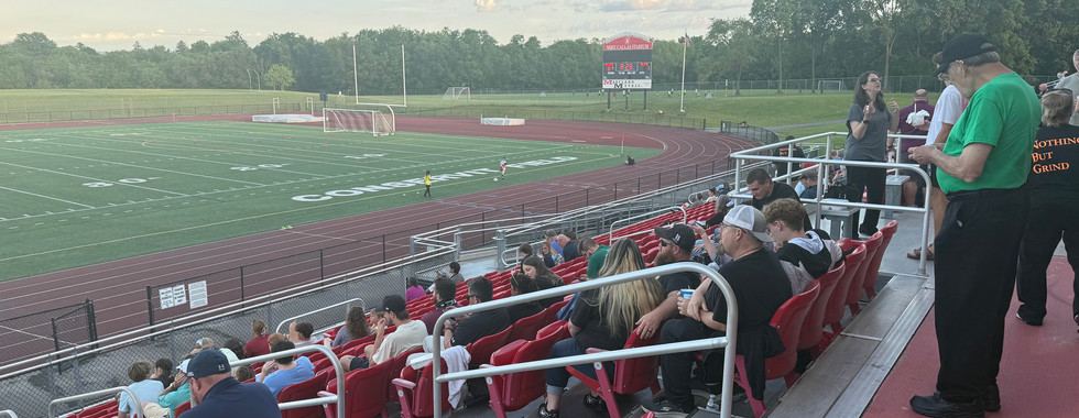 Looking towards the goal line and fans at a Hub City FC soccer game. There are fans in red chairback seats