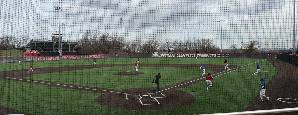 The view from behind home plate at Talbot Field for a Catholic University Cardinals game. There is a turf field.