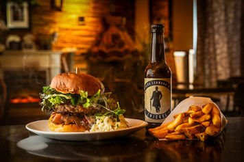 Burger mit Pommes und Bier in gemütlicher Atmosphäre fotografiert
