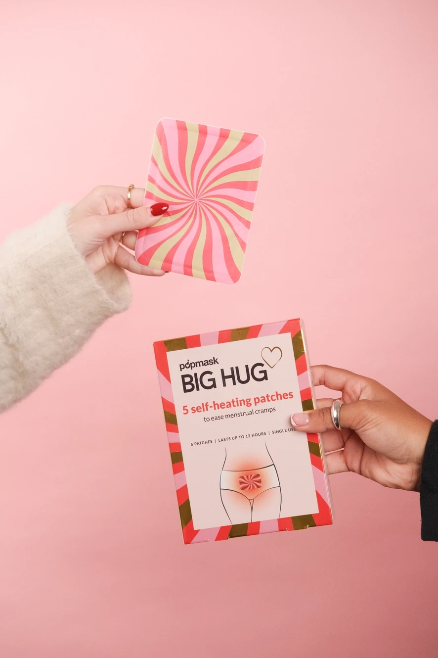 Thumbnail: Hands holding pink and white Big Hug self-heating patches Mellofina