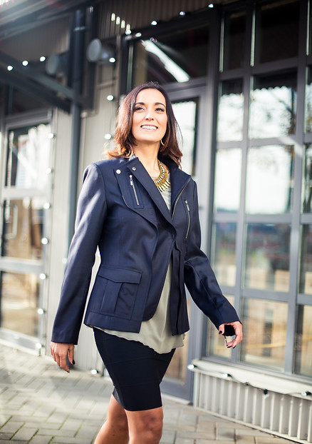 Nafissa walks down the street in a leather jacket and hoops, smiling
