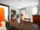 sala da pranzo con tavolo, divano, credenza, una finestra e la porta d'ingresso