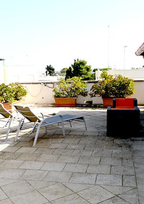 Terrazza dell'attico con sdraio, divano, fioriere e vetrata dell'attico