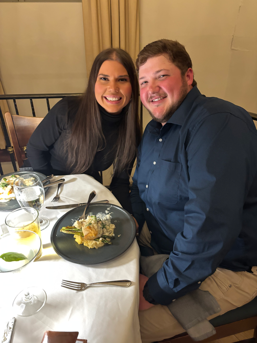 Smiling couple at a restaurant table with food and drinks. Date night.