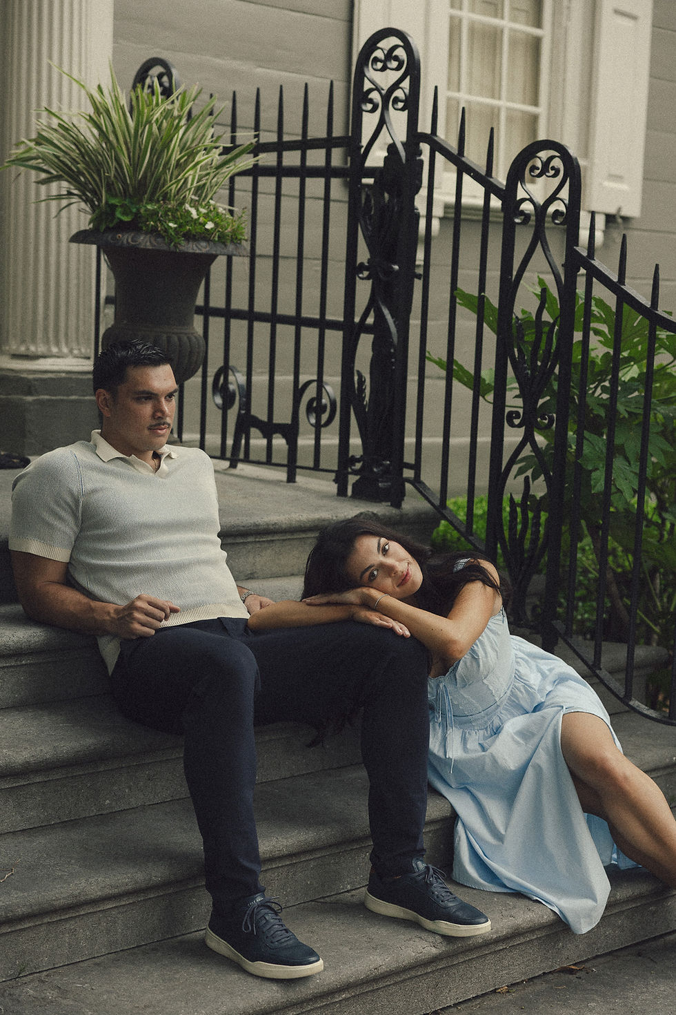 Couple sitting on stone steps outside a house.