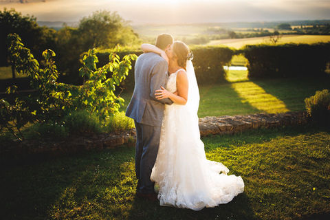 Bride and Groom by the lavender wall with the sun shining