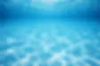 Clear underwater view of a clean swimming pool with bright blue water and sun reflections