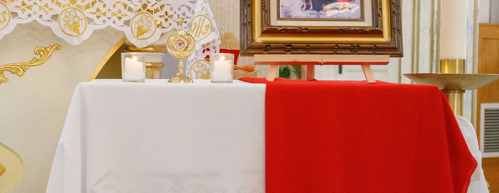 A close-up of a framed religious image displayed on a stand near the altar, with candles and flowers.