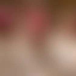 Clergy in white robes and pink caps sit solemnly in a dimly lit church; one man bows his head in prayer.