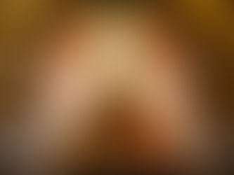 Crucifix with white drapes displayed in a church, set against a marbled red wall. Floral arrangements at the base convey reverence.