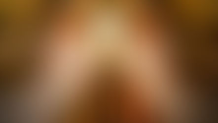 Crucifix with white drapes displayed in a church, set against a marbled red wall. Floral arrangements at the base convey reverence.