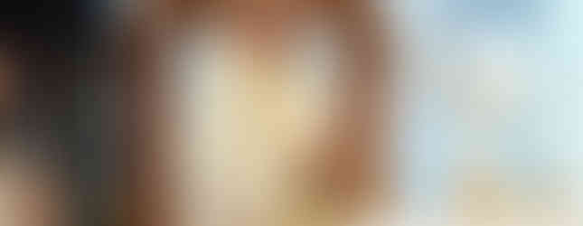 A bishop in elaborate robes stands at an altar, smiling during a ceremony. The setting is ornate with gold and floral accents.