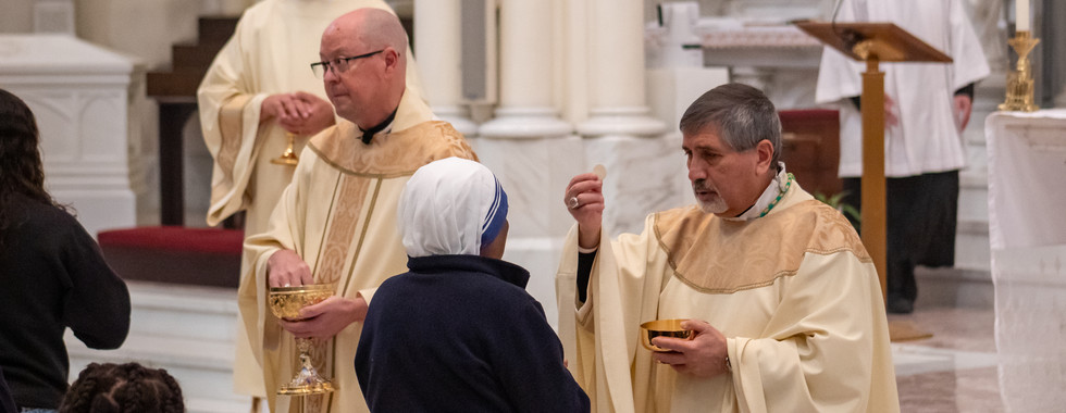 A bishop distributes Communion to a woman wearing a head covering inside the church.