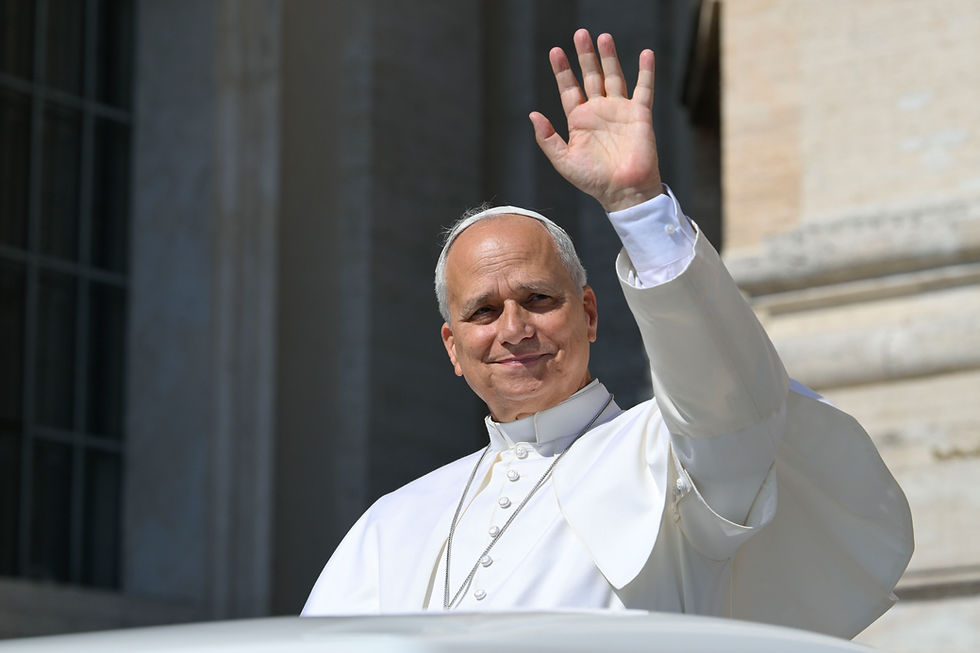 El papa León, con sotana blanca, saluda con la mano desde un balcón; fondo de piedra y luz soleada.