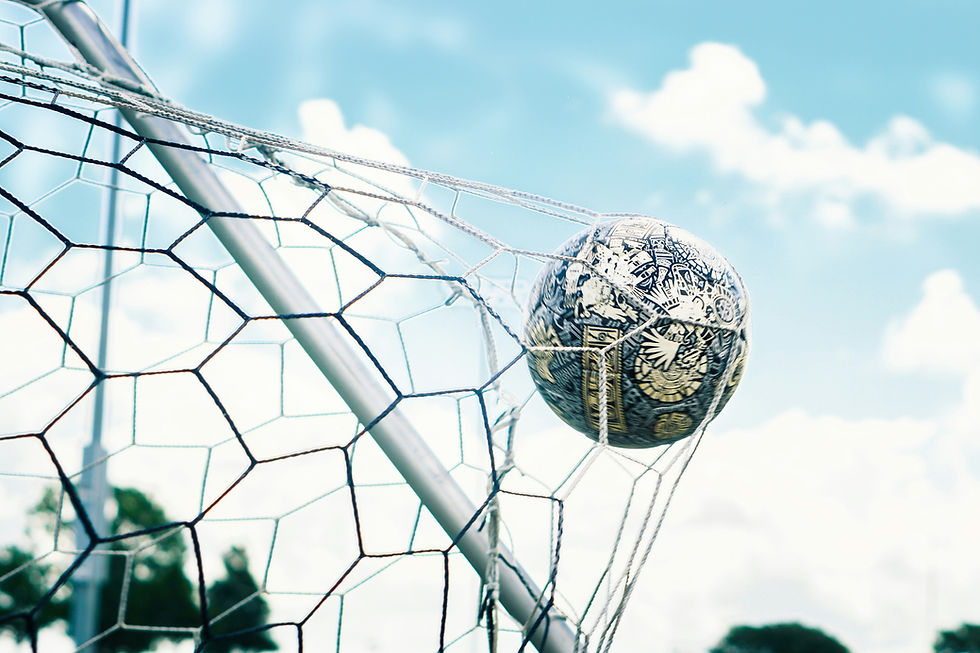 Soccer ball caught in a white net on a goal frame against a bright blue sky with clouds.