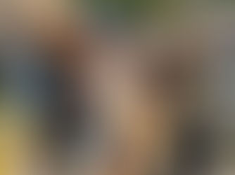 Five friends walking near a pond, laughing and carrying books. They wear casual fall attire. Background shows trees and buildings.