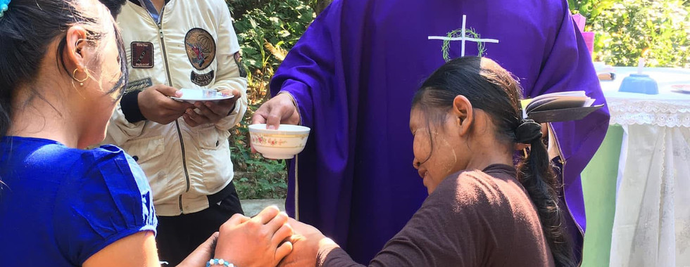 El padre Paul bautiza a un bebé recién nacido durante una visita pastoral misionera a una aldea.