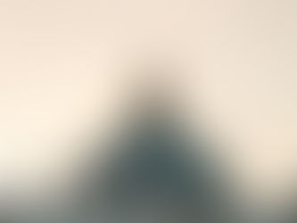 St. Peter's Basilica dome at sunset against a pale sky, flanked by statues. A serene and majestic architectural scene.