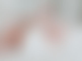 Baby lying on a white bed, wearing a white onesie, with legs playfully raised. Soft, calm atmosphere. No visible text.