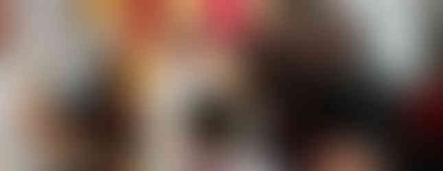 Priest in white robe giving communion to people, including a child, in a decorated church. Warm lighting, Christmas decor in background.