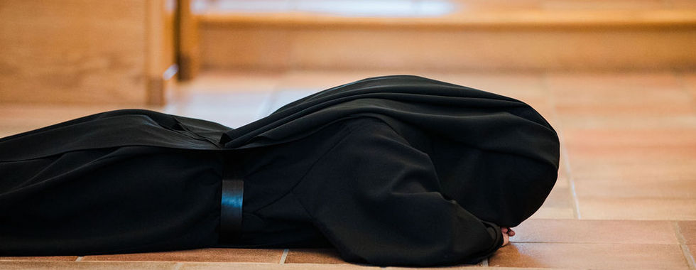 A religious sister lies prostrate on the chapel floor in a traditional act of humility and surrender during her solemn profession.