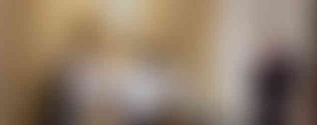 A woman kneels in prayer before a decorated altar with a statue of Mary and a glass reliquary in an ornate chapel.