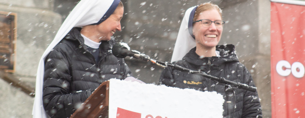 Two religious sisters smile at the podium during the snowy Colorado March for Life event.