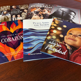 A collection of colorful magazines with various texts and images, including a smiling child, on a wooden table. Themes include faith and Christmas.
