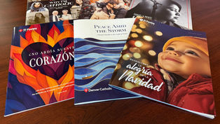 A collection of colorful magazines with various texts and images, including a smiling child, on a wooden table. Themes include faith and Christmas.