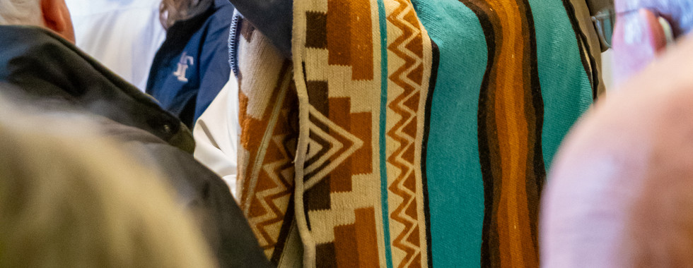 The bishop smiles while taking a selfie with a parishioner in a busy church hallway.