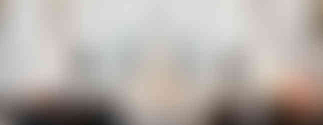 A congregation in a grand church watches priests in white robes at an ornate altar. The setting is serene with high ceilings and statues.