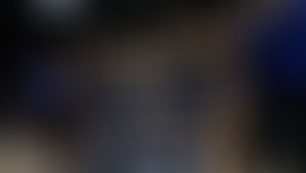 Girls' basketball team celebrates championship win, holding trophy and "State Champions" banner in stadium. Team wears black uniforms.