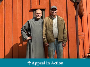 Two smiling men pose in front of an orange wooden building. One wears a gray robe, the other a brown jacket. Text: Appeal in Action.