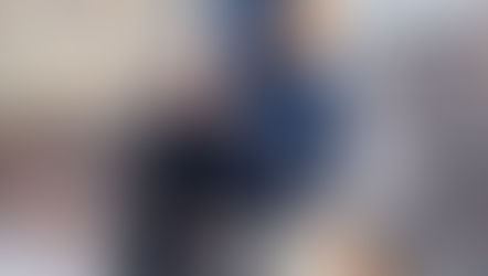 A man in clerical attire talks to a boy with a backpack outdoors. The setting is around leafless shrubs, with a sunny, cheerful mood.