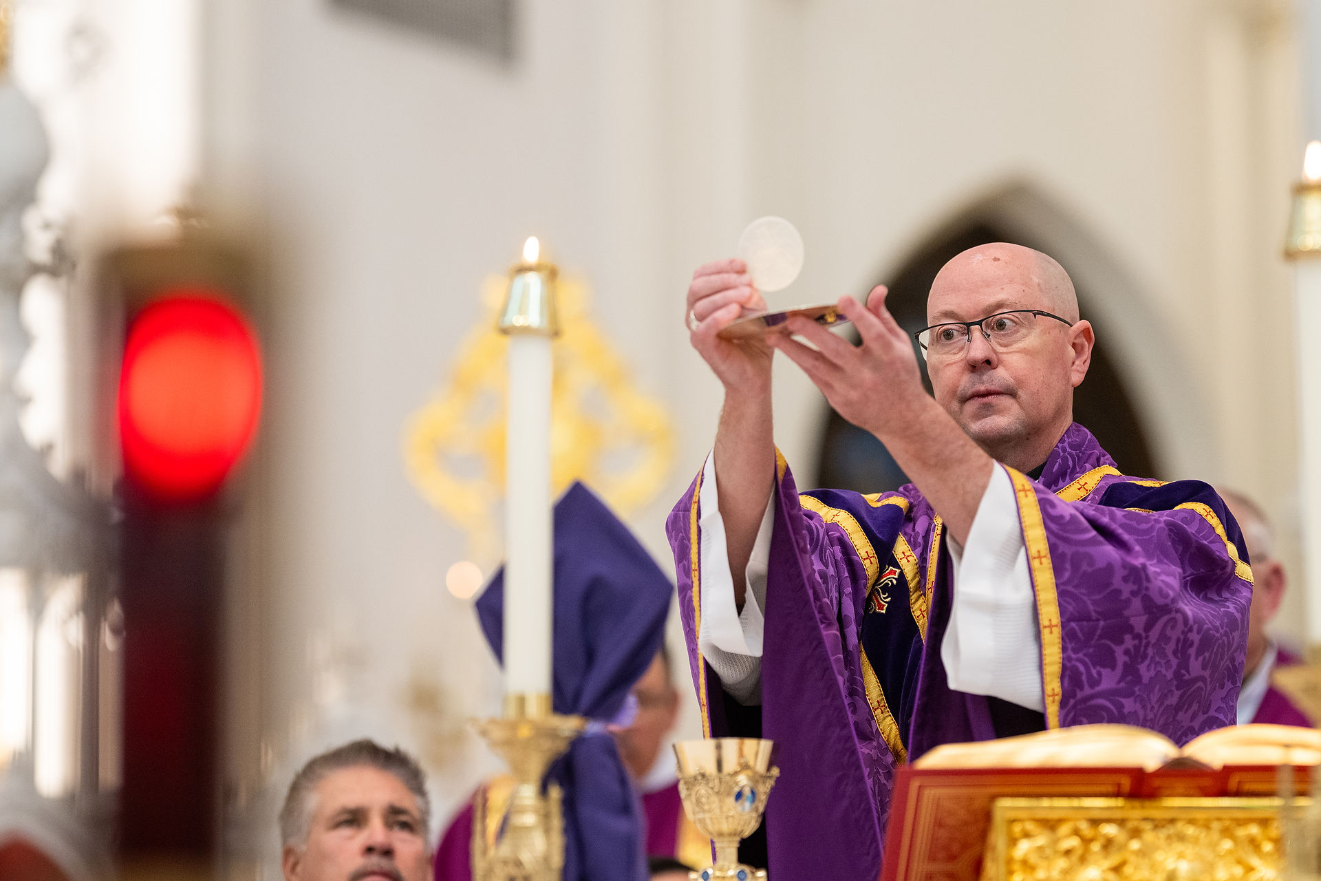 Obispo eleva la hostia consagrada durante la consagración en la Eucaristía.